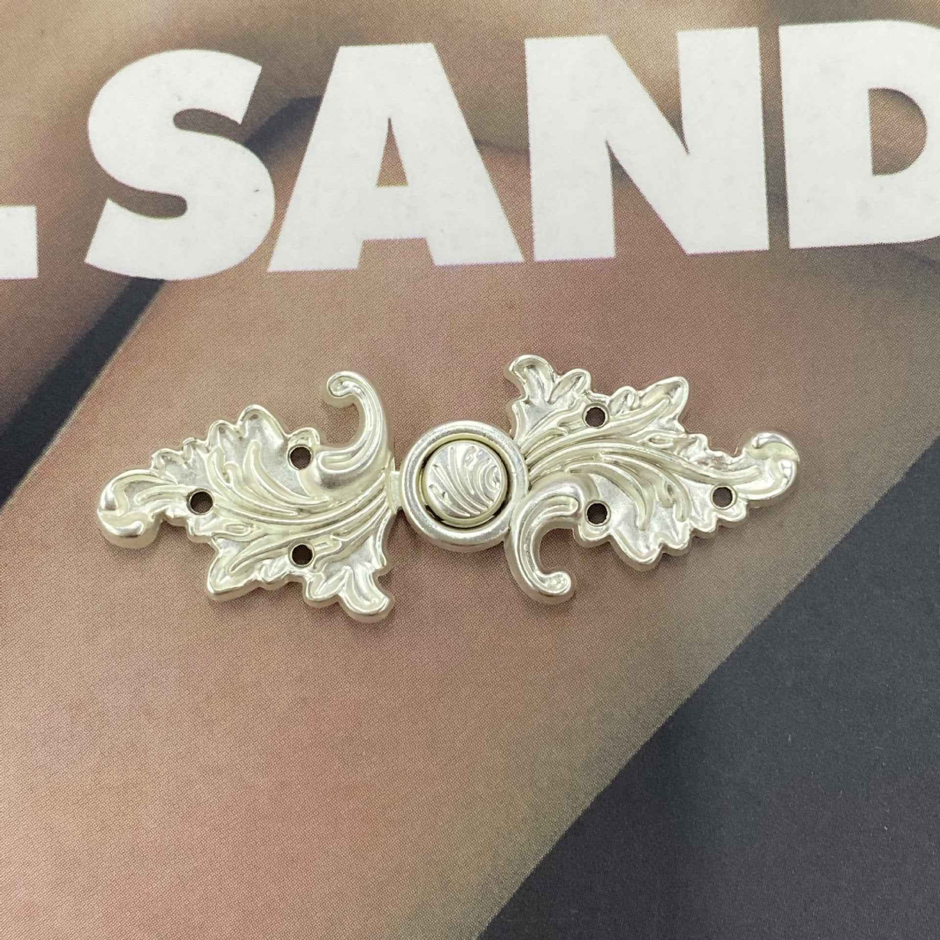Silver-tone metal frog button (Style 10), leafy scroll ornaments with central circular emblem