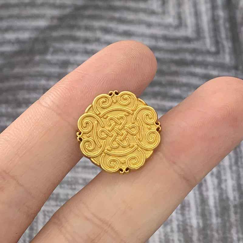 Matte gold Chinese knot motif metal button, round with raised swirl pattern.