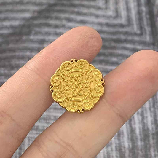 Matte gold Chinese knot motif metal button, round with raised swirl pattern.