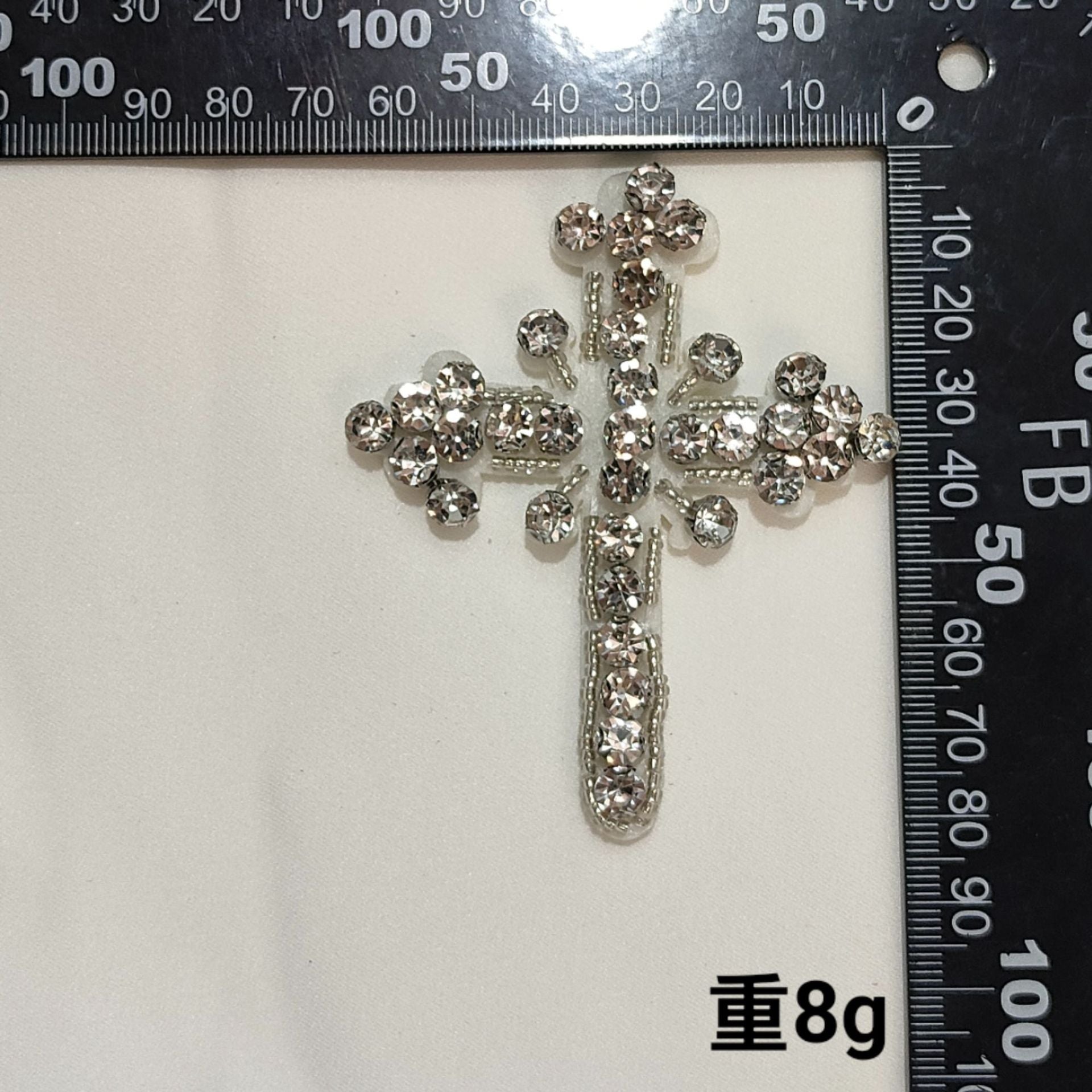 Silver-toned cross badge patch with clear rhinestones and long beaded center