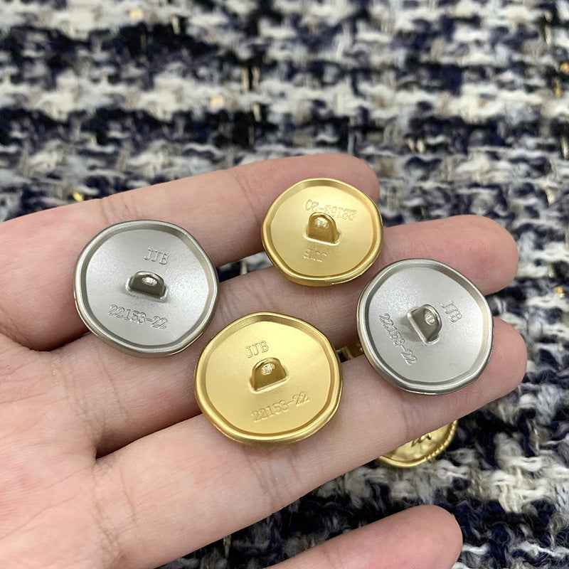 Rückseitenansicht: Metallknöpfe gold und silber mit eingraviertem Steg/Öse und Prägung.