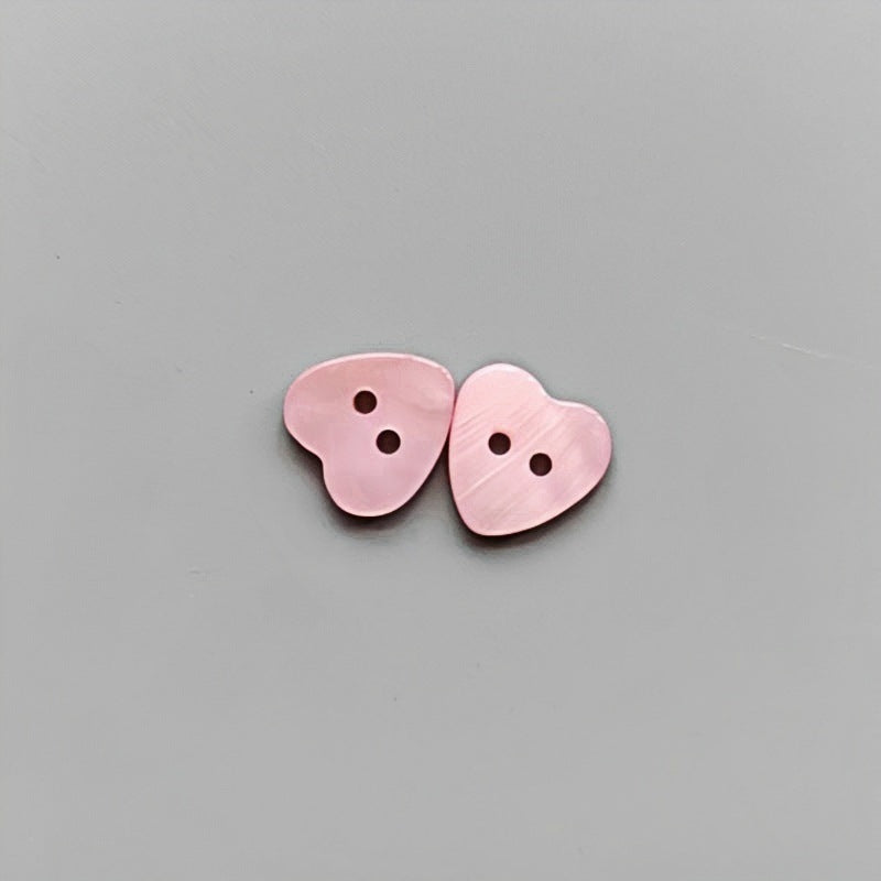 Pink heart-shaped 2-hole shirt buttons for children, two pieces shown.