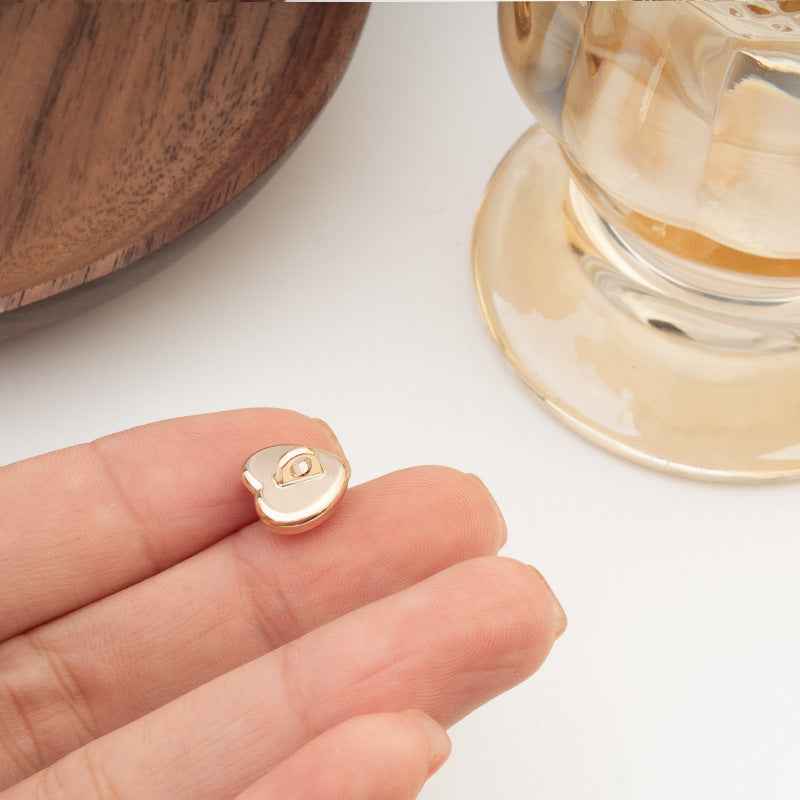 Single heart-shaped button with iridescent finish and gold-tone edge, close-up on hand