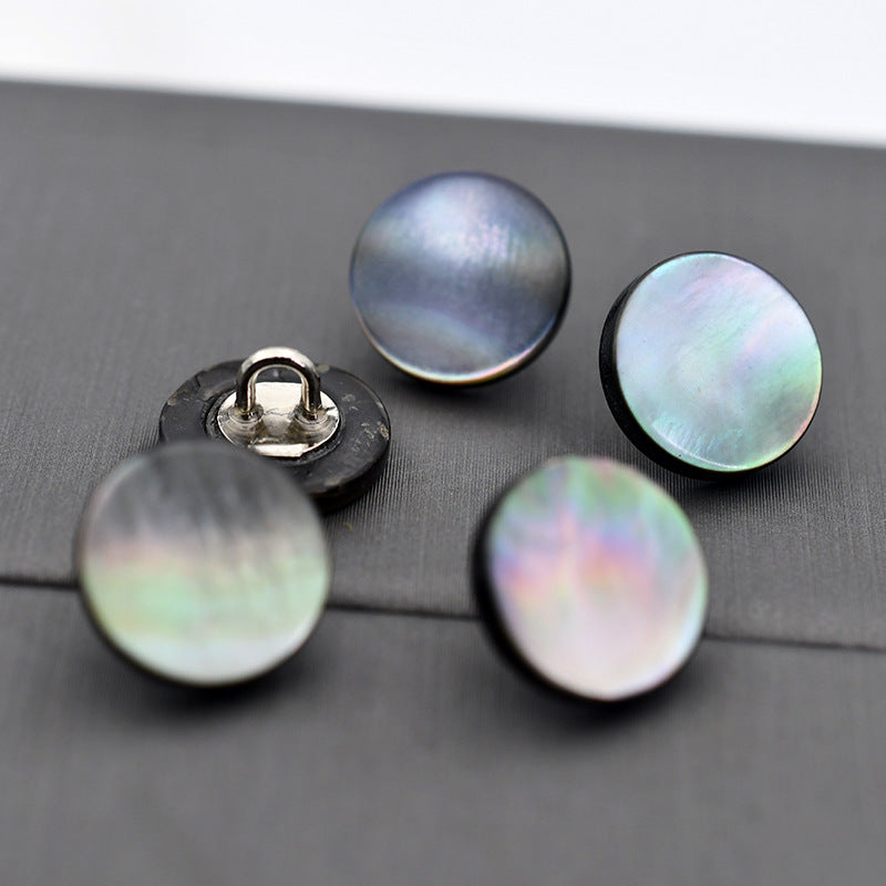 Dark and iridescent mother-of-pearl shell round buttons with metal shank, close-up