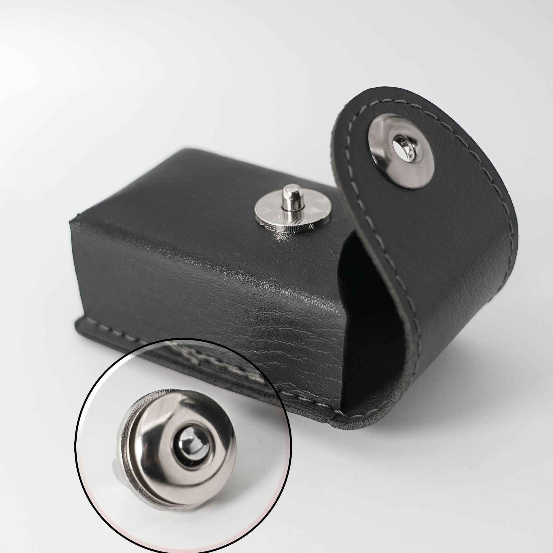 Magnetic snap eyelet closure on black strap, round metal button with stitching