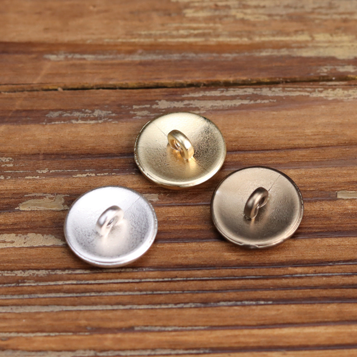 Round metal shank buttons with embossed wave face; gold and silver with visible back shank.