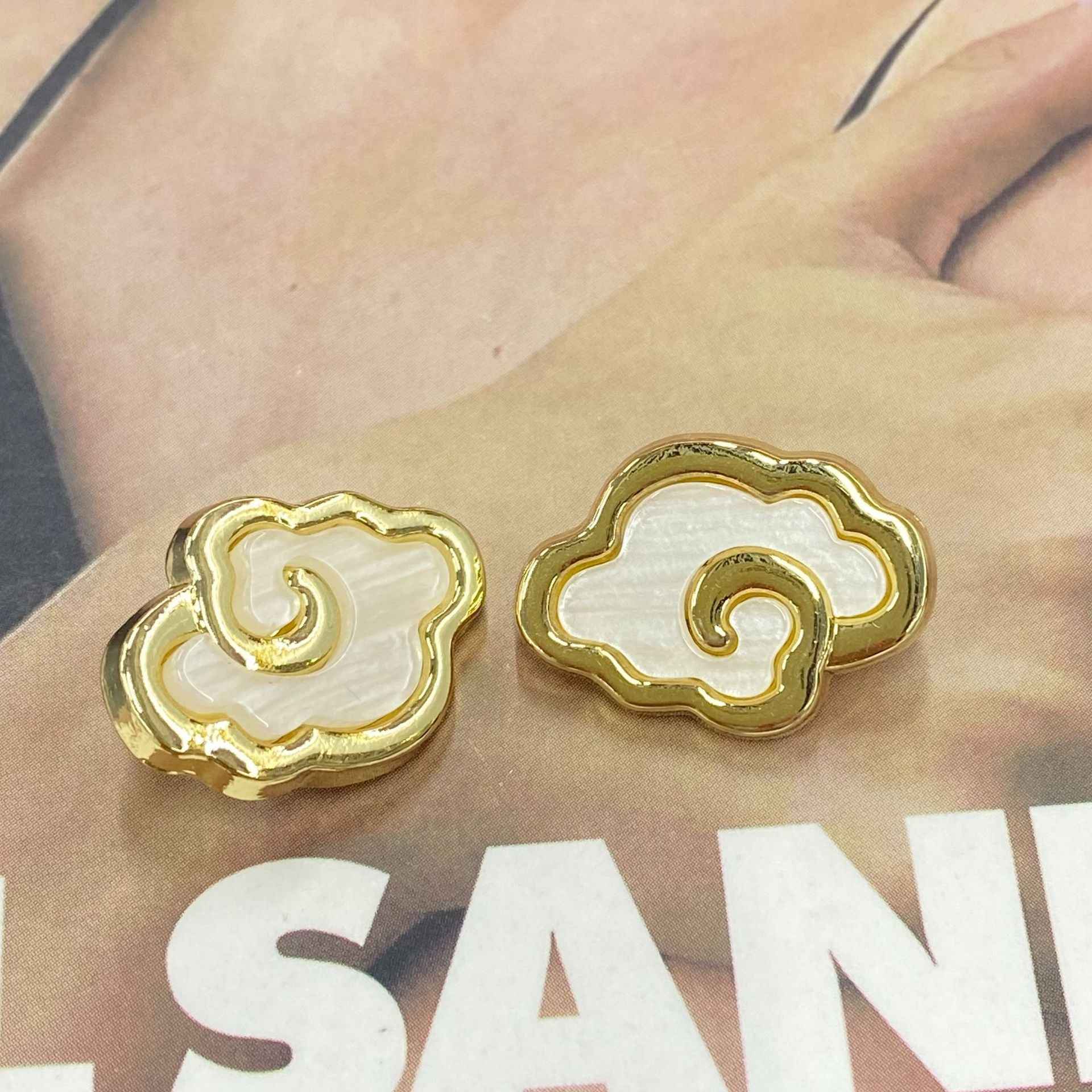 2 goldfarbene Wolkenknöpfe mit geschwungener Einfassung und weißem Stein-Finish
