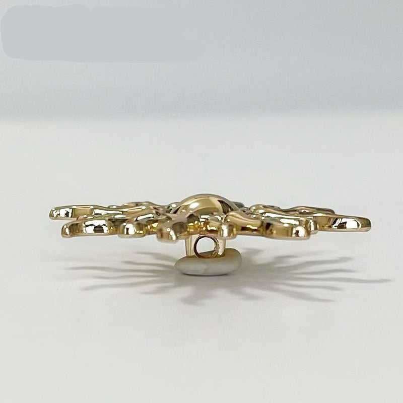 Gold-tone sun-shaped metal shank button underside, central eyelet visible