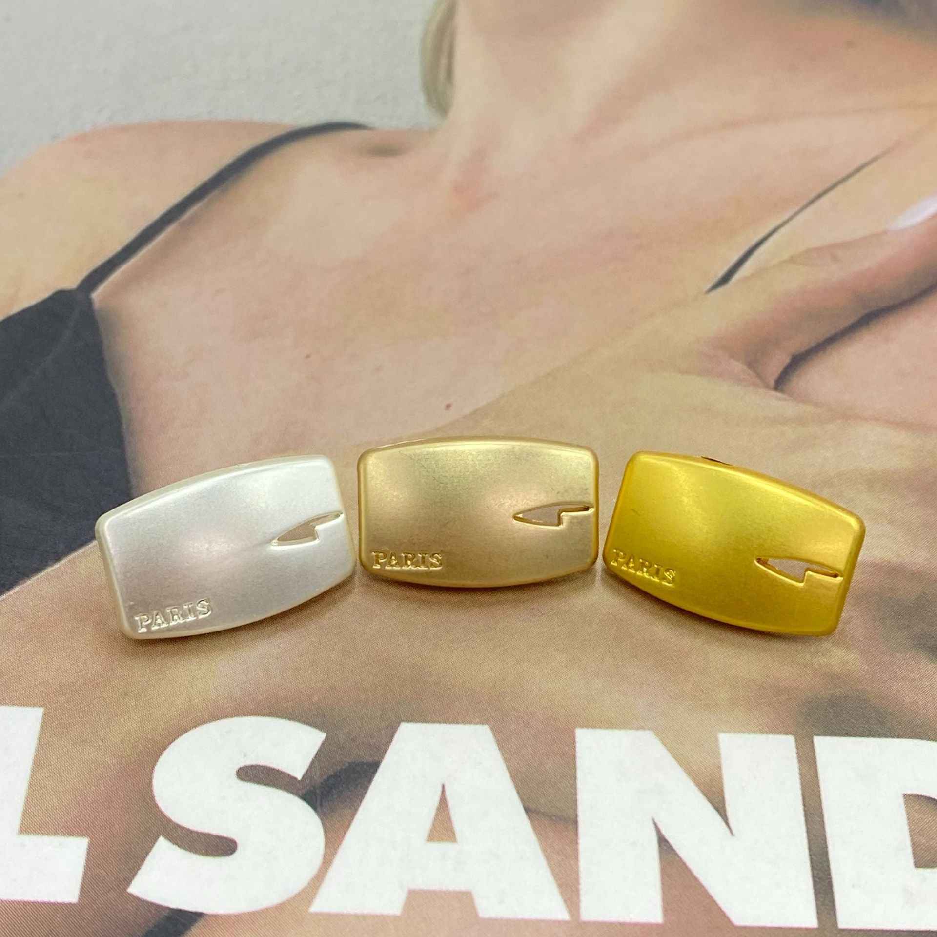 Rectangular Paris knife buttons on palm: silver, light gold, and gold tones
