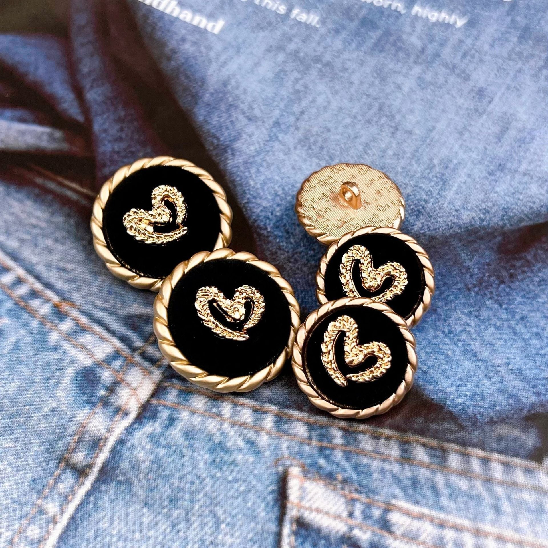 Set of black round sewing buttons with gold braided edges and heart motifs