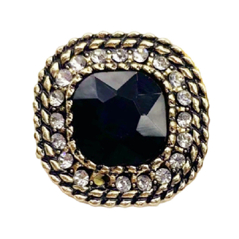 Close-up vintage square metal shank button with dark crystal center and clear rhinestones