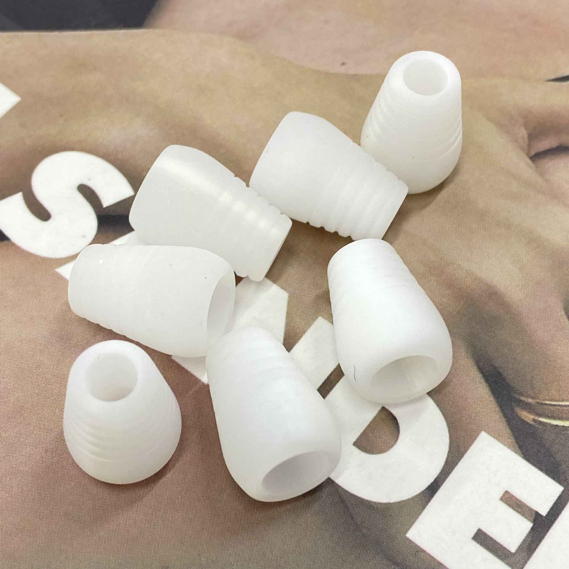 White resin cord end stoppers with ribbed bell ends and center hole
