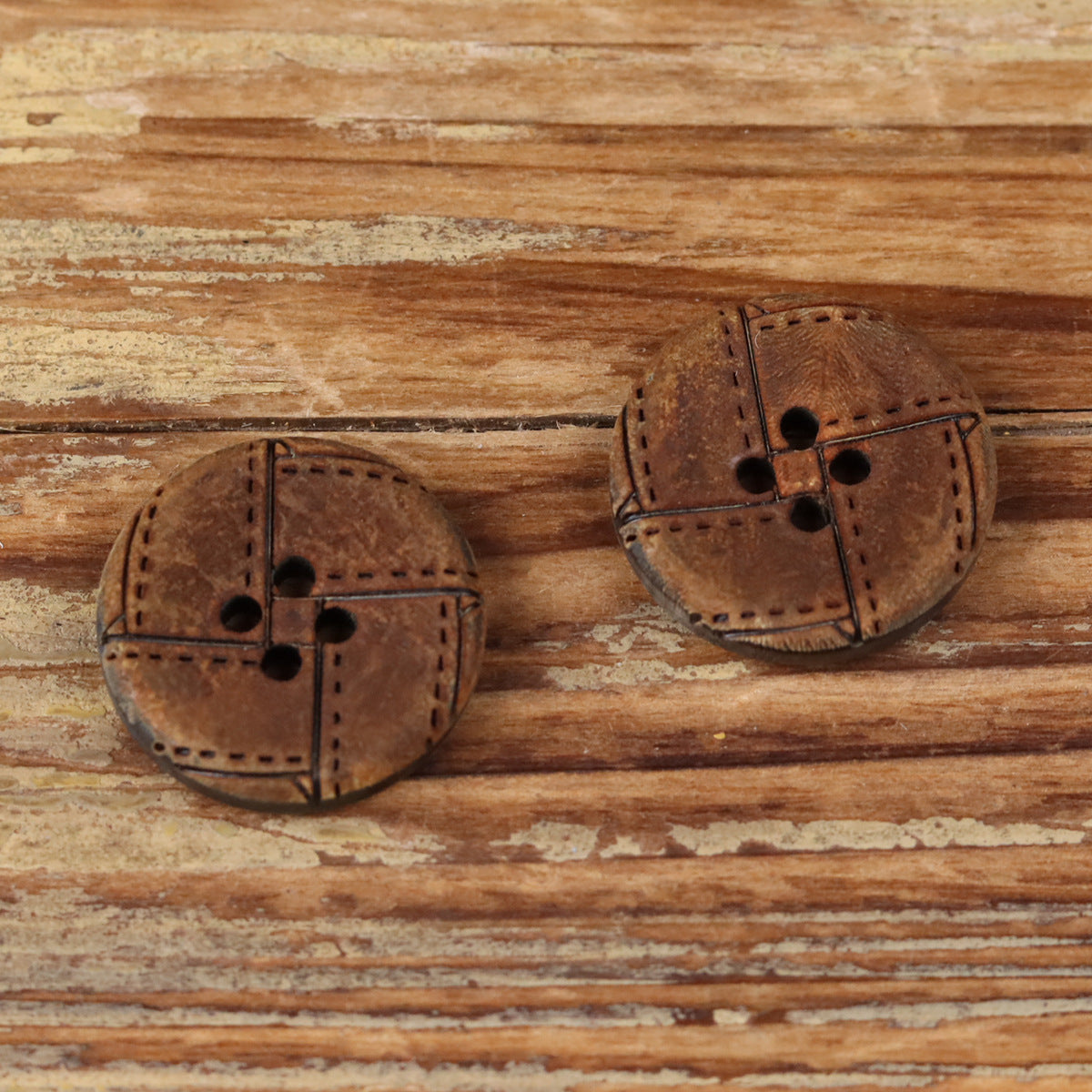 Two round 4-hole horn buttons with geometric engraved lines and stitched edges