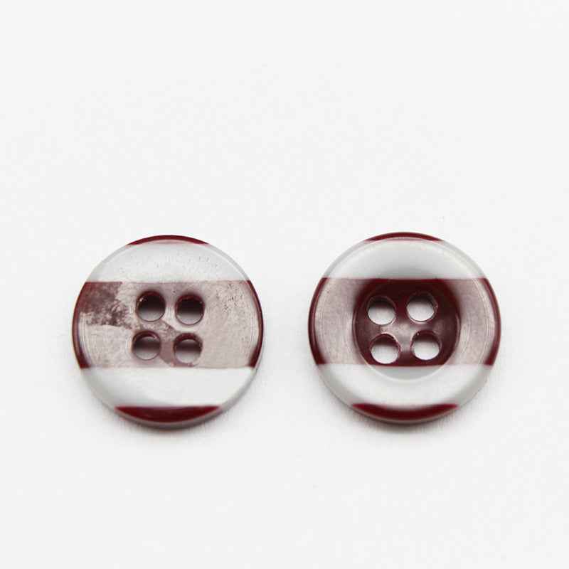 White round button with four holes and dark red/brown stripe, top view