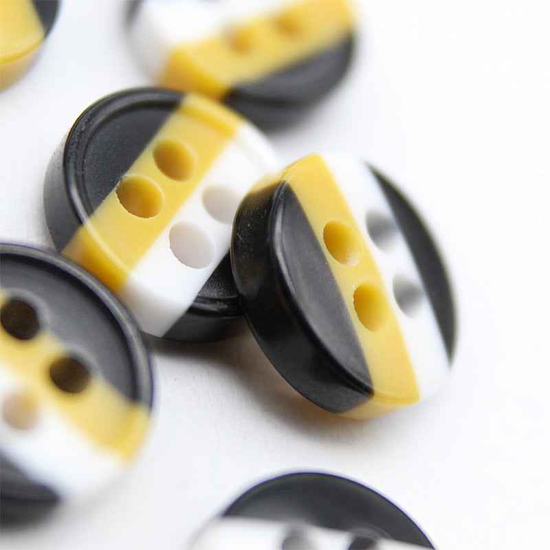 Round 4-hole resin buttons, angled close-up; black and yellow with white stripe