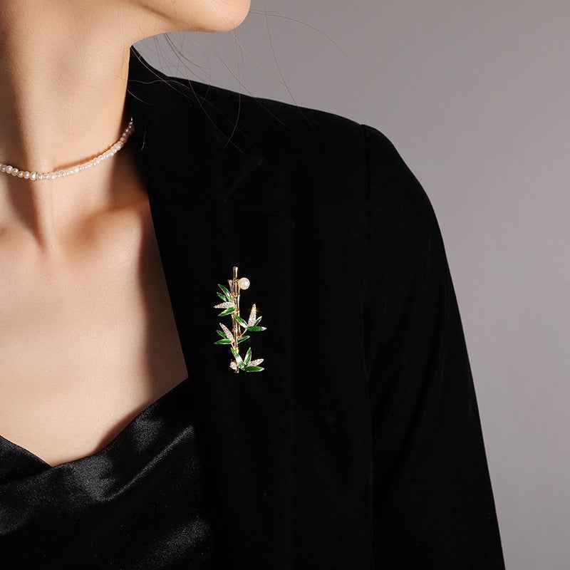 Gold bamboo pearl brooch on a dark coat lapel, green enamel leaf details