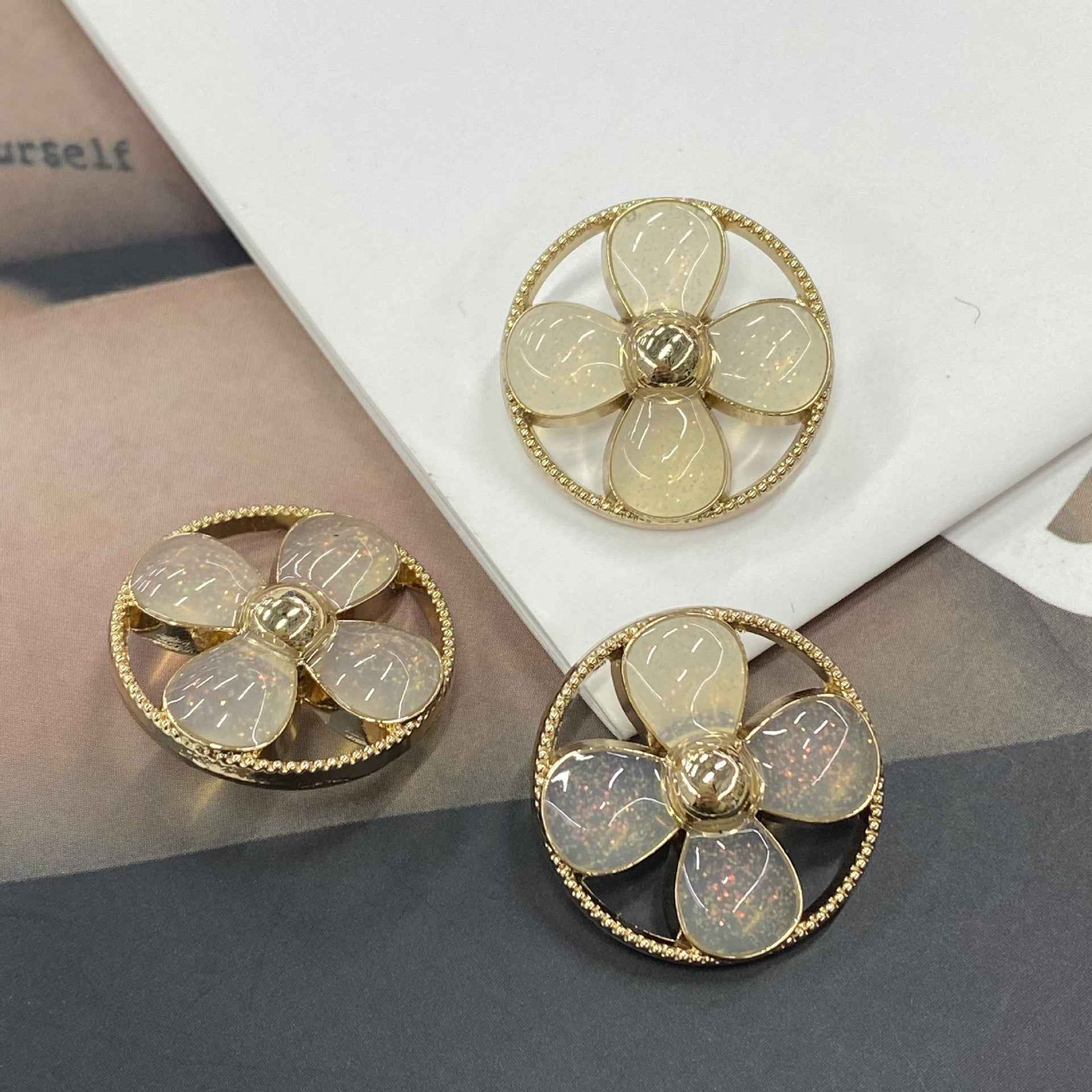 Round clover shank buttons with beige/clear petals, gold-tone rim and 5-petal flower center