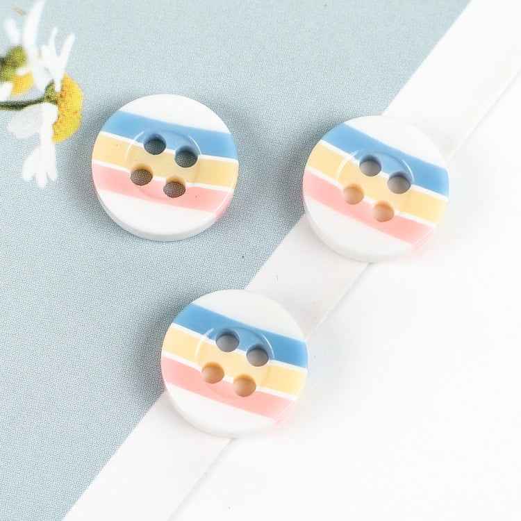 Ronde knoop met vier gaten, gestreept blauw/gelb/rosa, witte buitenrand