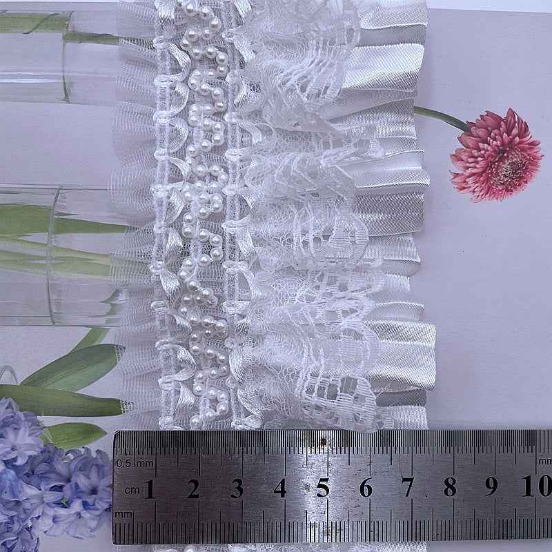 White lace ruffle trim with pearl bead borders, measured beside a 1–10 cm ruler