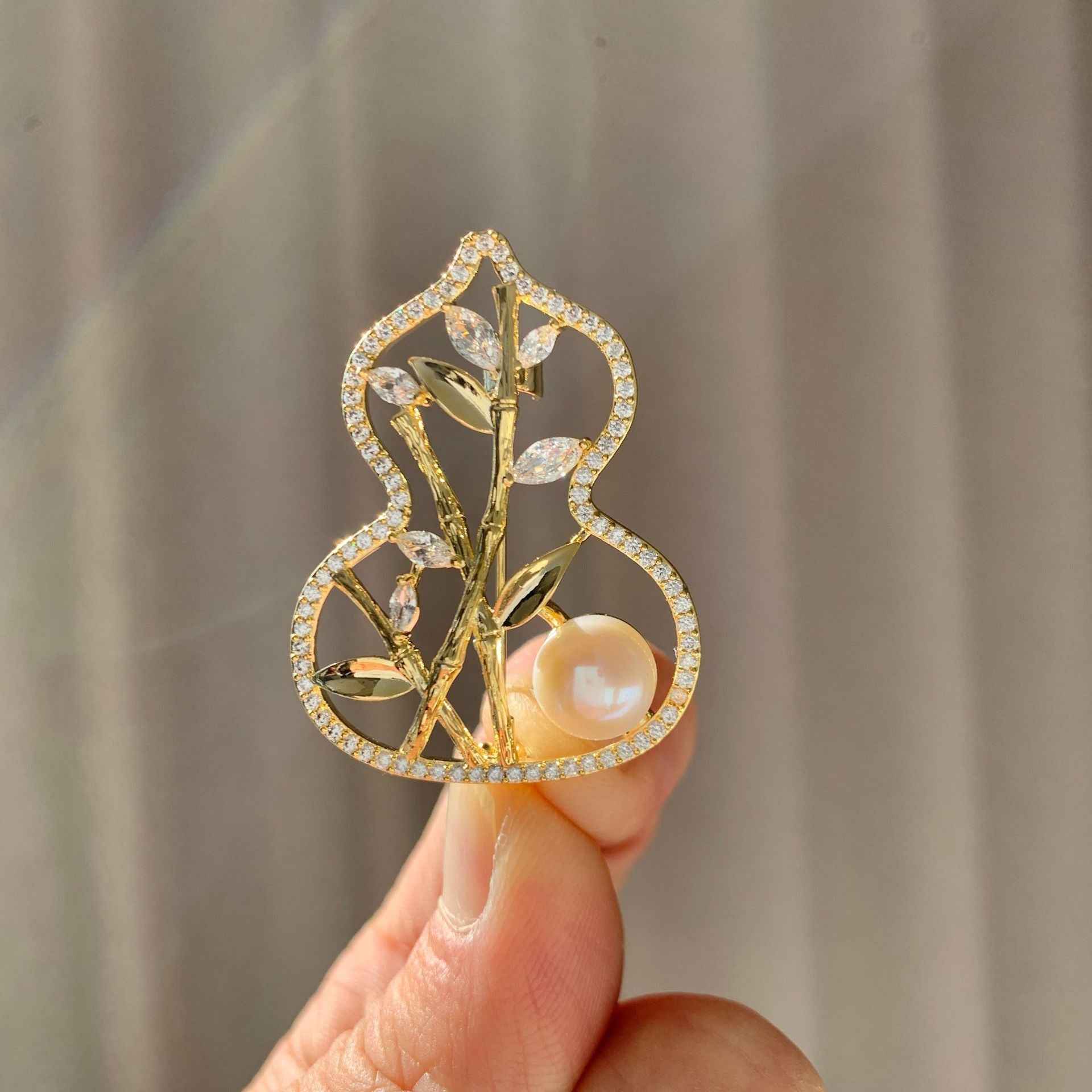 Copper bamboo gourd brooch in hand, white pearl set in gold-tone frame