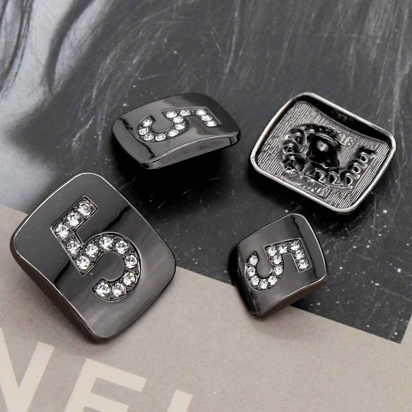 Number 5 shank buttons in dark gunmetal tone with clear rhinestones