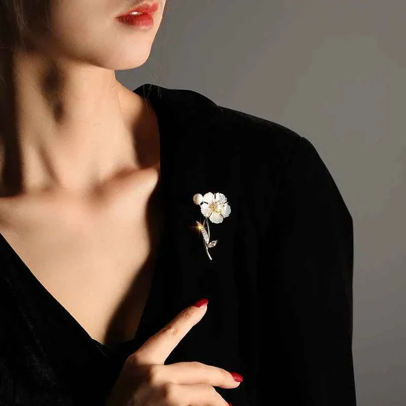 Camellia brooch pin on black clothing: white pearl flower with gold-tone zircon detailing