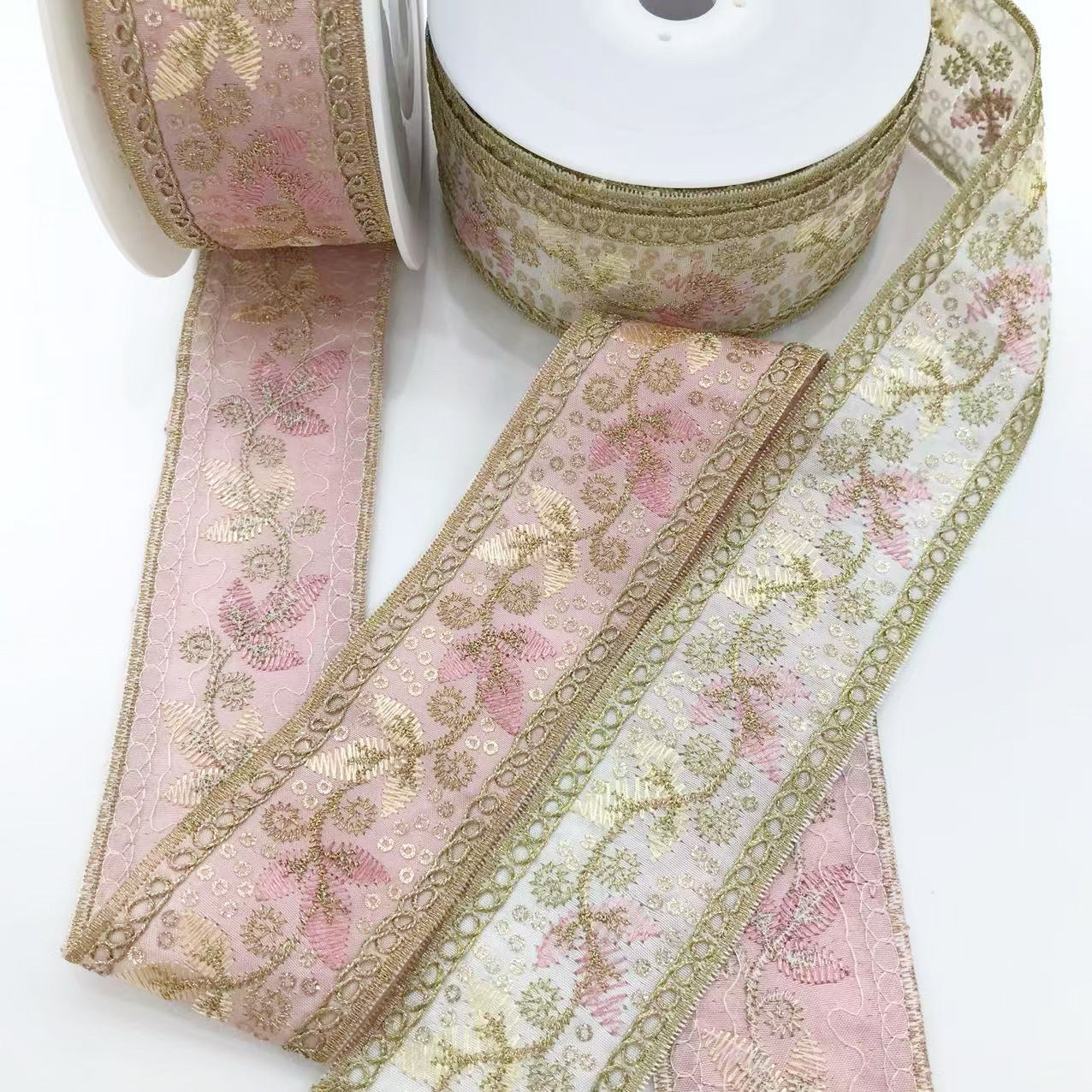 Goldene Stickborte mit rosa und cremefarbenen Ornamenten, eingefasst mit Kordelrand