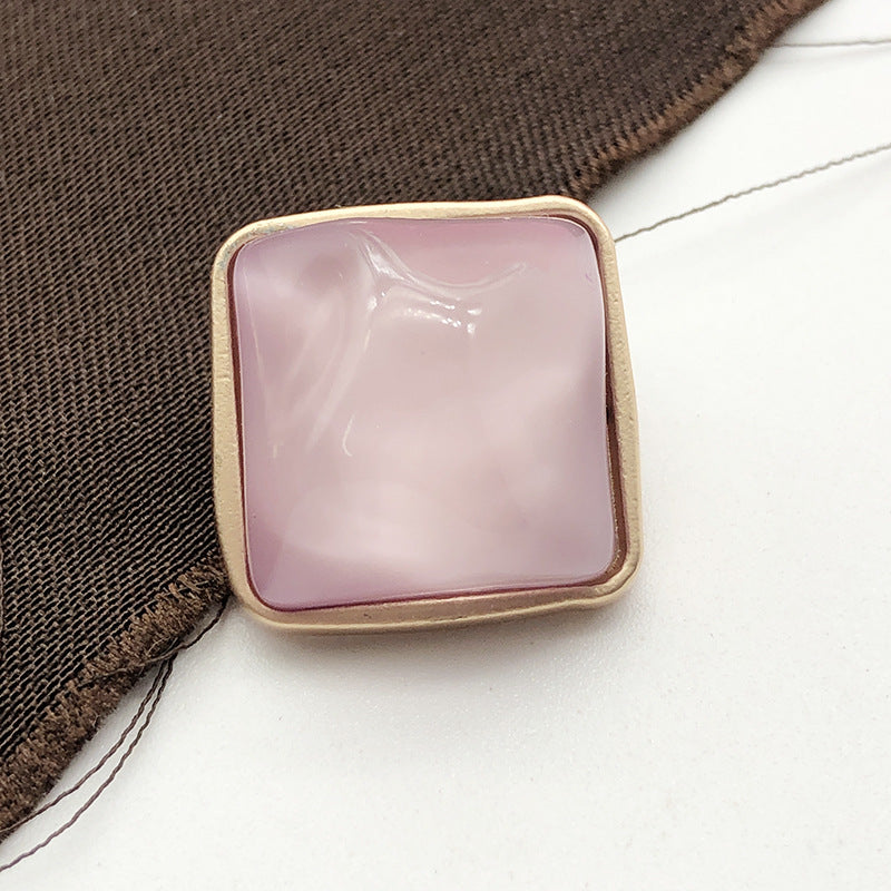 Square stone-look coat button, pale pink, gold-tone metal shank, close-up