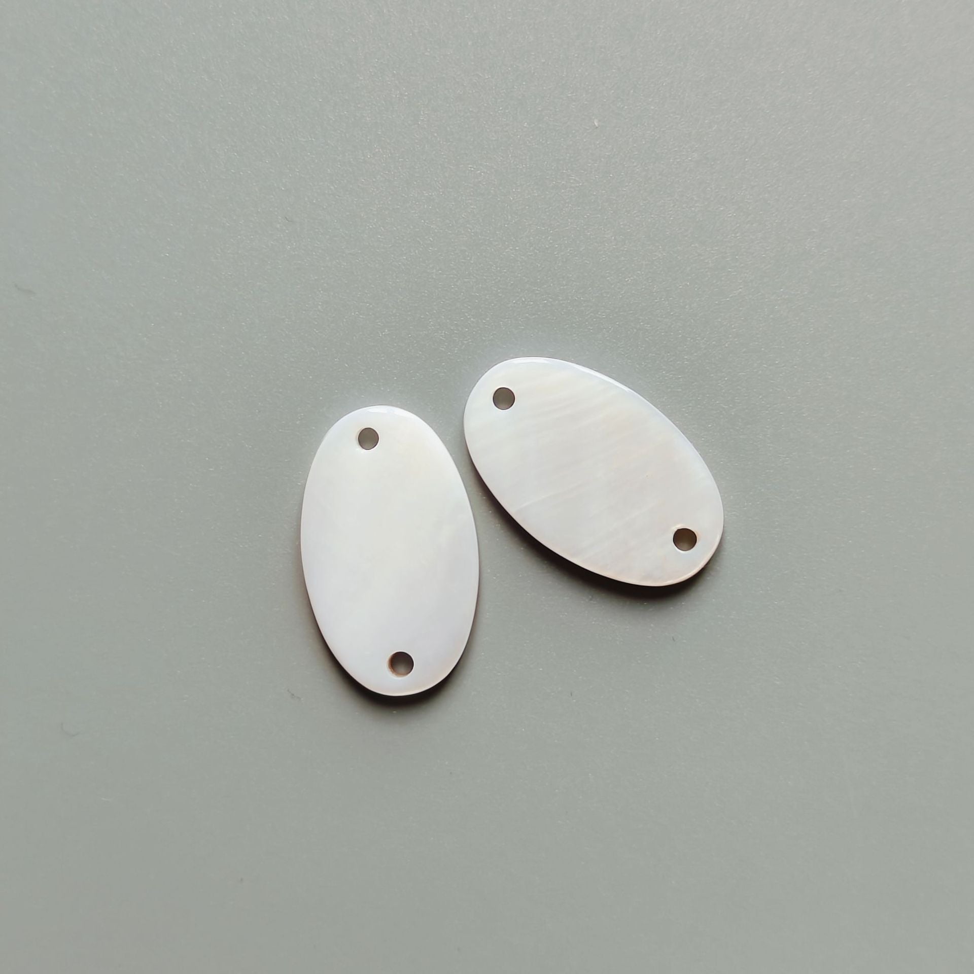 Natural white oval shell buttons with two holes, 32/34L, close view