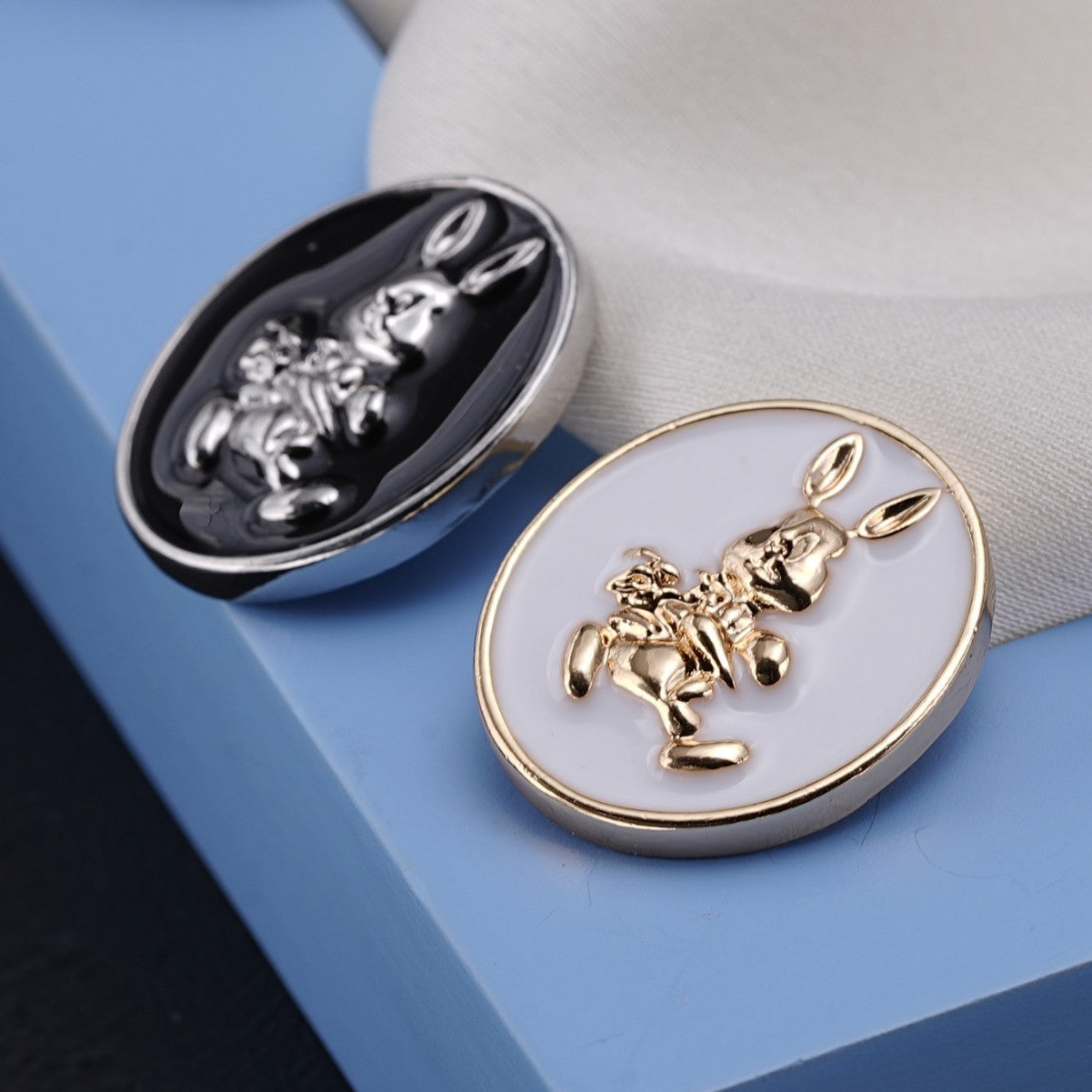 Two oval shank rabbit buttons: white gold and black silver fronts