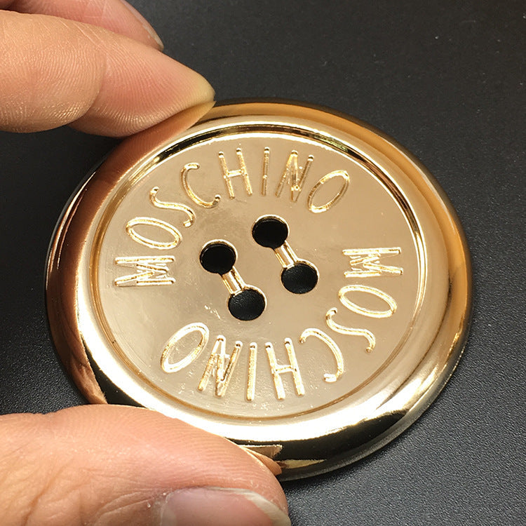 Nahaufnahme goldfarbener 70-mm Rundmetallknopf mit vier Löchern, dünner Rand