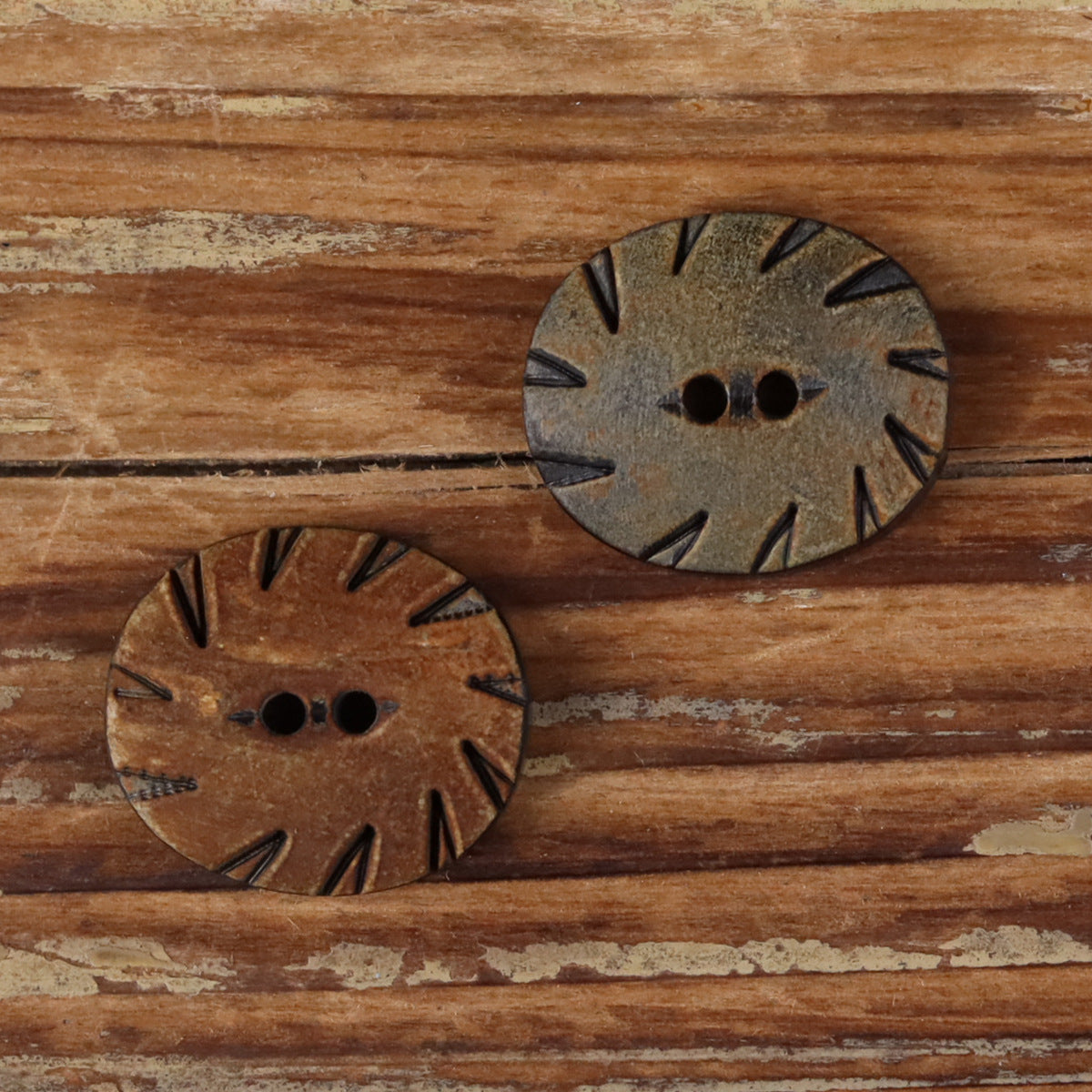 Oval two-hole horn buttons, brown and grey with carved radial cutout detailing.