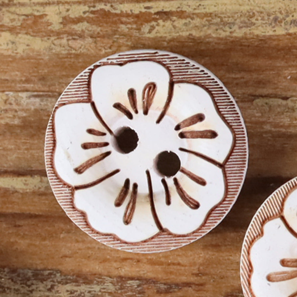 Round 2-hole wood button with painted floral pattern in white with brown outline accents.