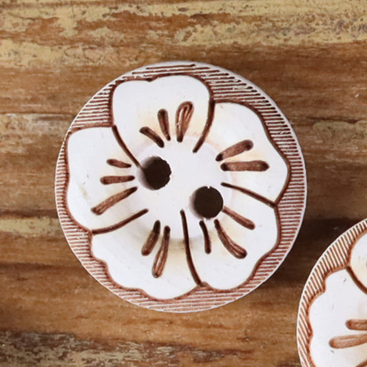 Round 2-hole wood button with painted floral pattern in white with brown outline accents.