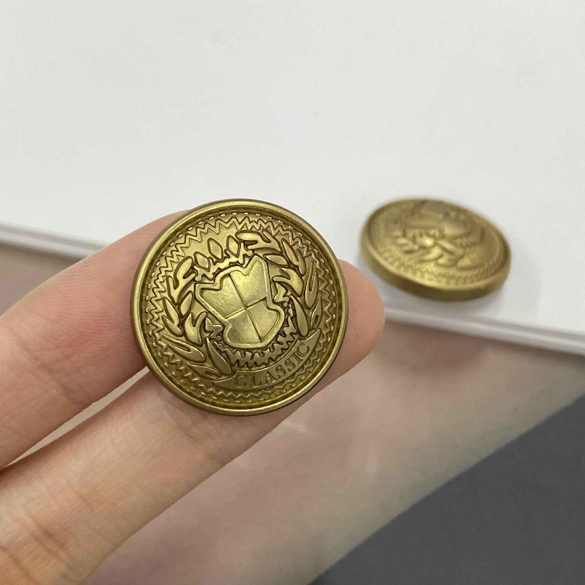 Metall-Schaftknopf 15–23 mm, rund, Peace-Schild, goldfarben, Nahaufnahme in Hand