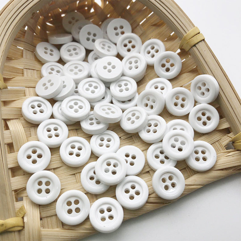 White 11.5mm round four-hole buttons arranged in a small woven tray.