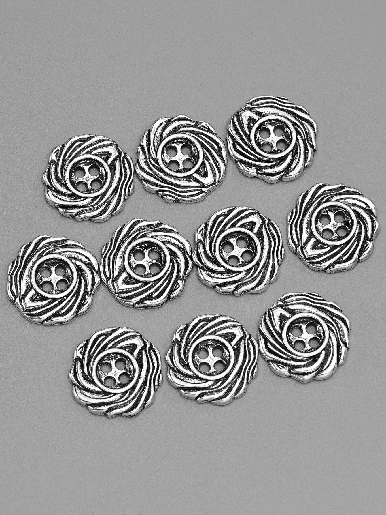 Silver 4-hole spiral metal buttons, multiple pieces arranged, front view