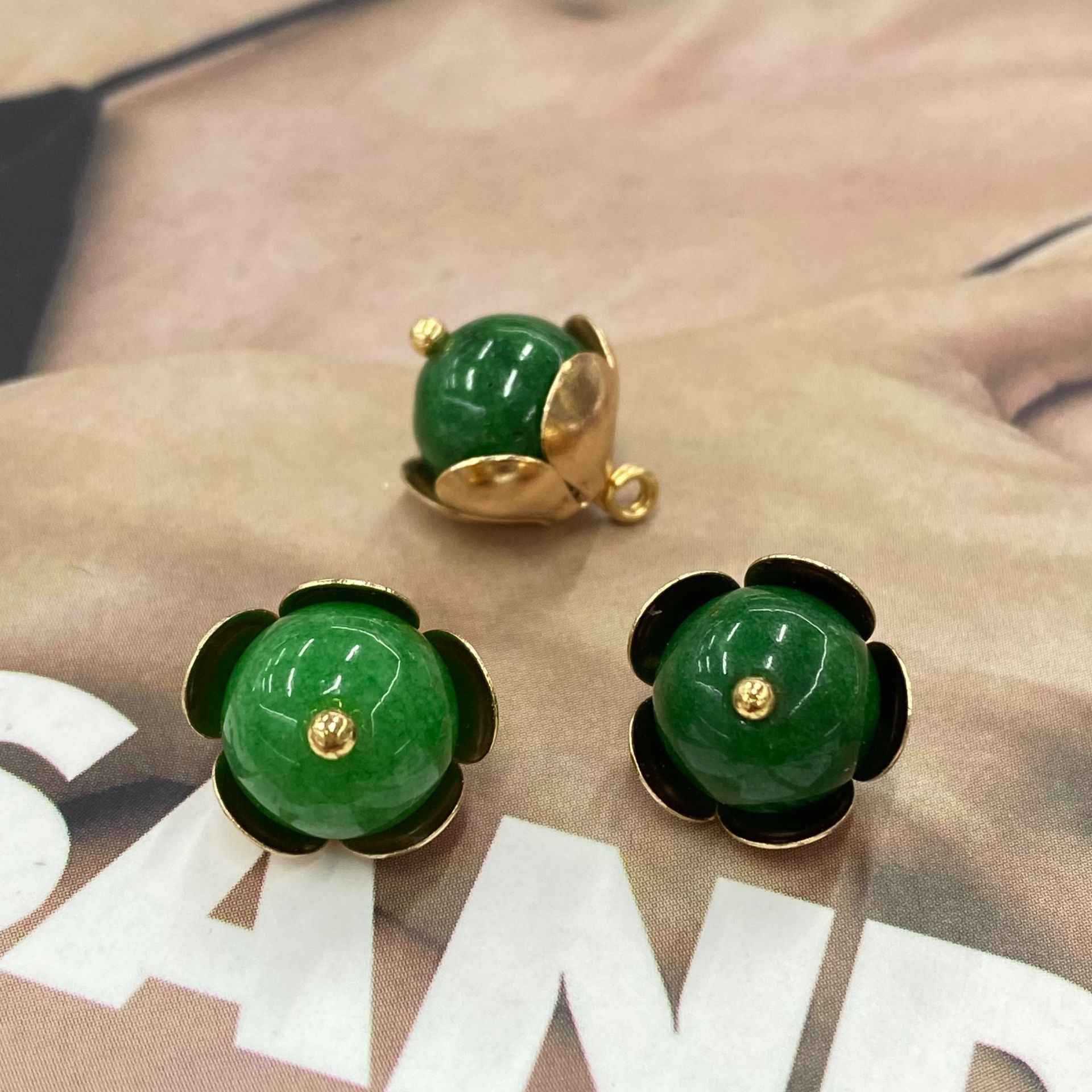 Close-up pair of green jade-style 12mm buttons with gold-tone flower metal base