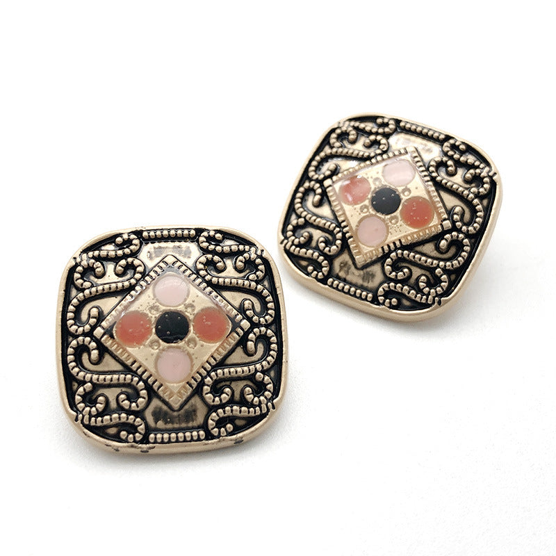 Metal shank button with multicolor gem center, pale background, and detailed filigree