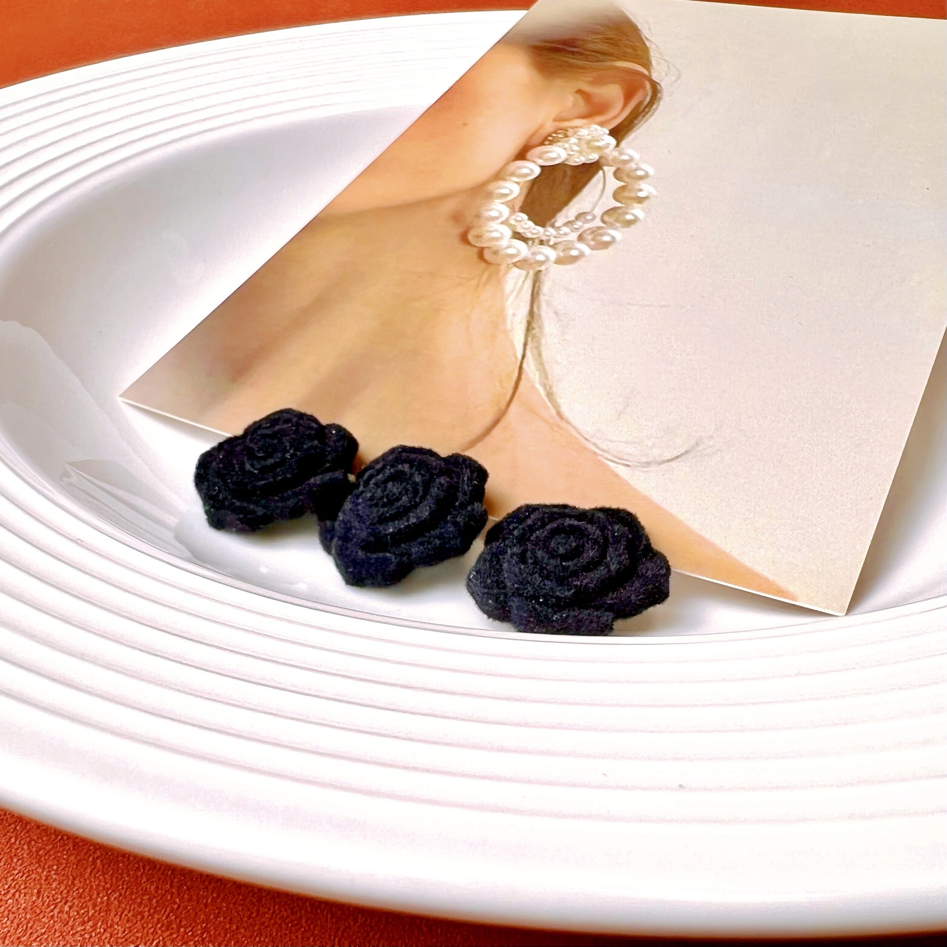 Set of dark plush rose buttons on backing card for sweater closures
