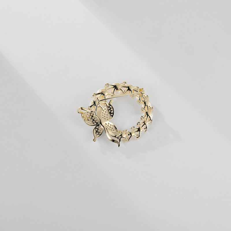 Rückseite der goldfarbenen Brosche: Perlenkranz und Schmetterlingsnadel mit Strass