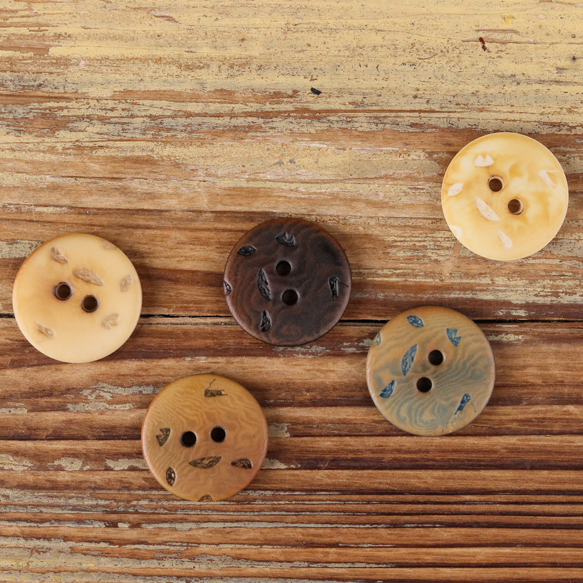 Natural round 2-hole buttons in mixed light and dark tones with blue accents