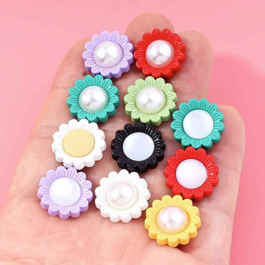 Hand holding colorful sunflower resin shank buttons with white pearl centers, mixed tones