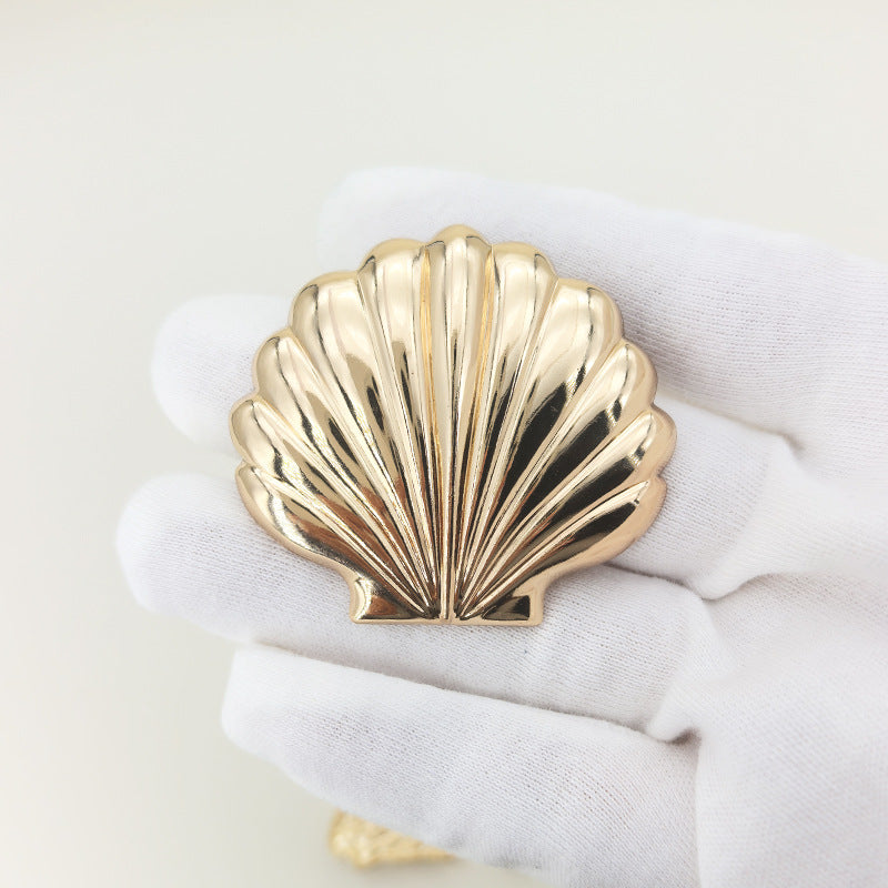 Gold shell brooch with safety-pin clasp, ribbed scallop design