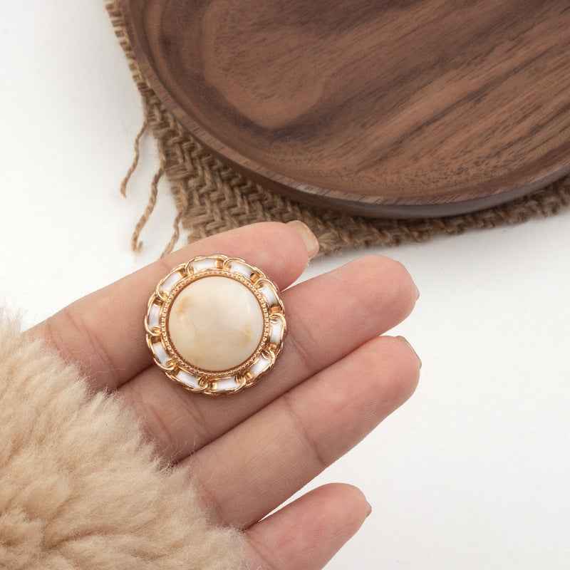 Beige resin shank button with gold-tone ornate ring and center