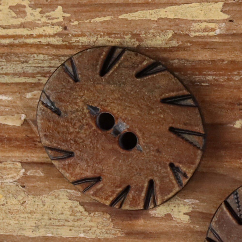 Oval two-hole horn button in brown with carved radial pattern and two-hole center.