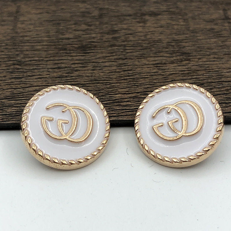 Zwei weiße runde G-Logo-Knöpfe mit goldfarbener Ziernaht und flachem Metallknopf
