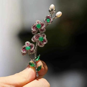 Plum blossom brooch pin: green center stones, ruby-red accents, silver-toned setting