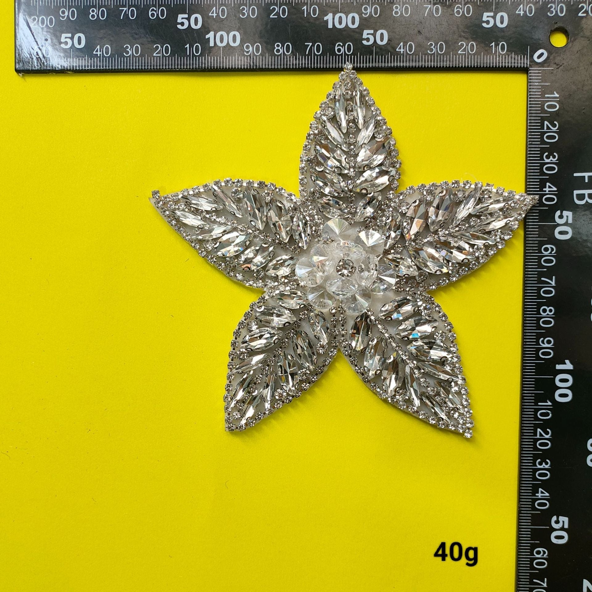 Silver rhinestone star-shaped flower patch with layered pointed petals, measured by ruler