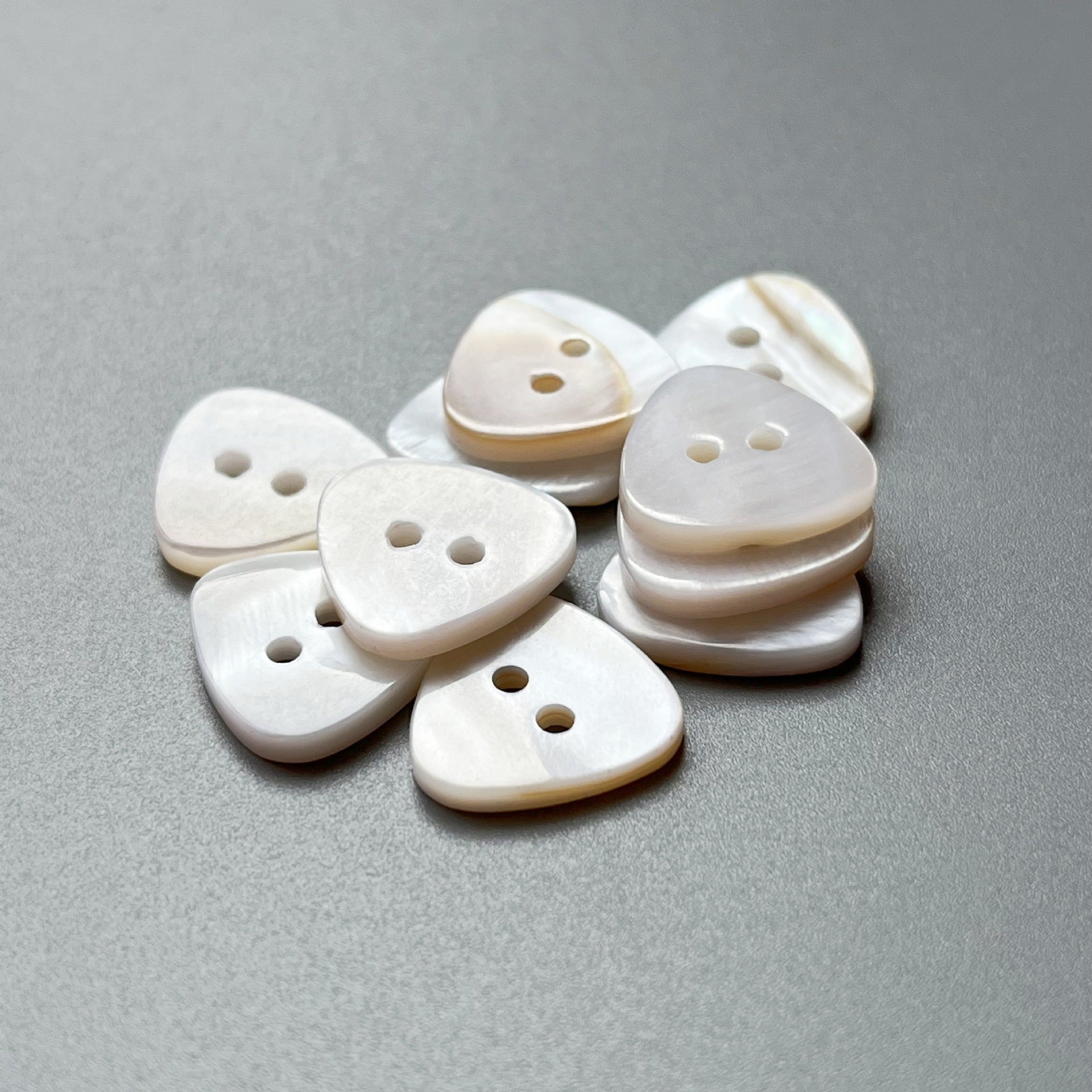 Natural shell triangular buttons, two-hole design; mixed angles in small group